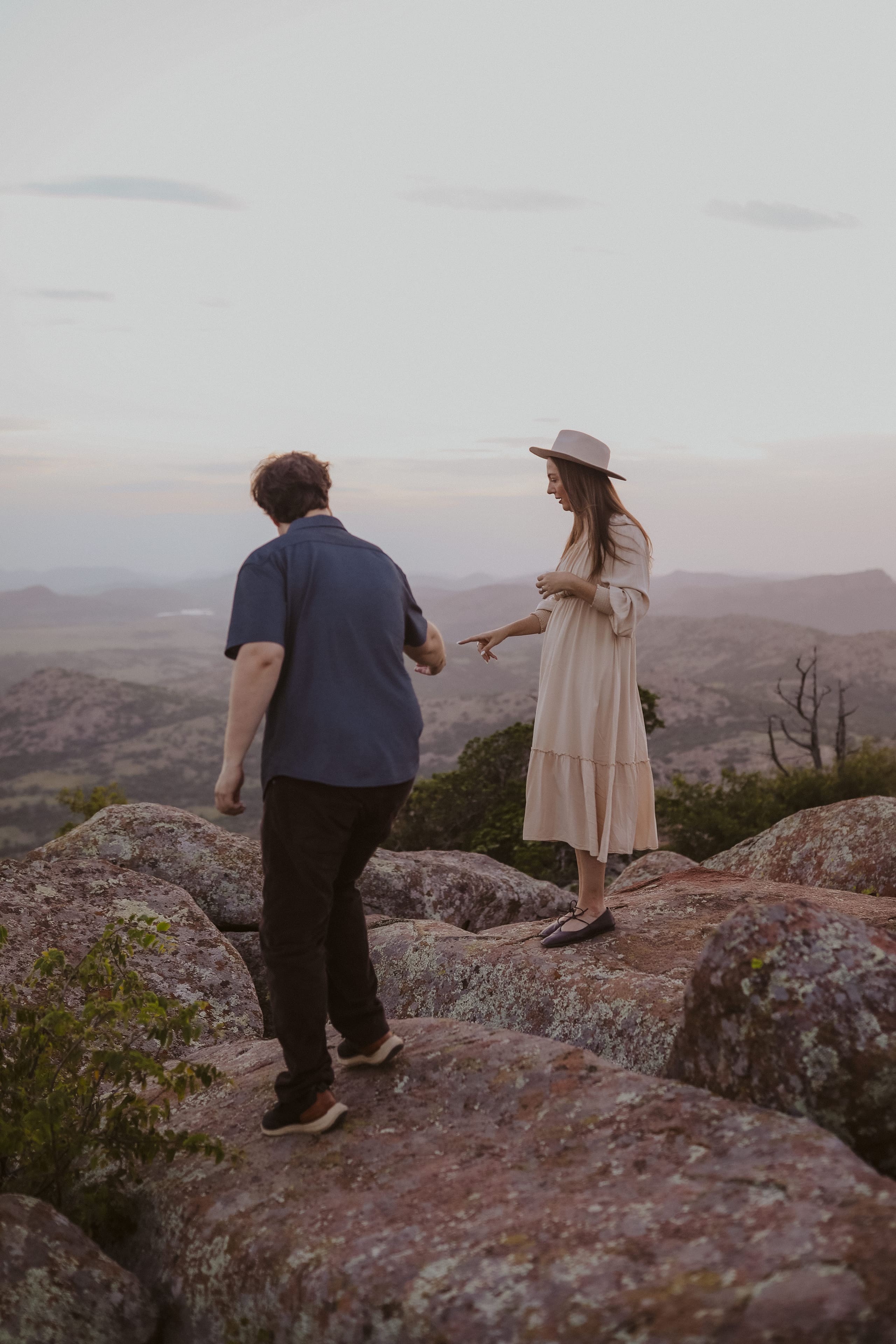 Picking their way across the boulders at dusk, her hat catching the light
