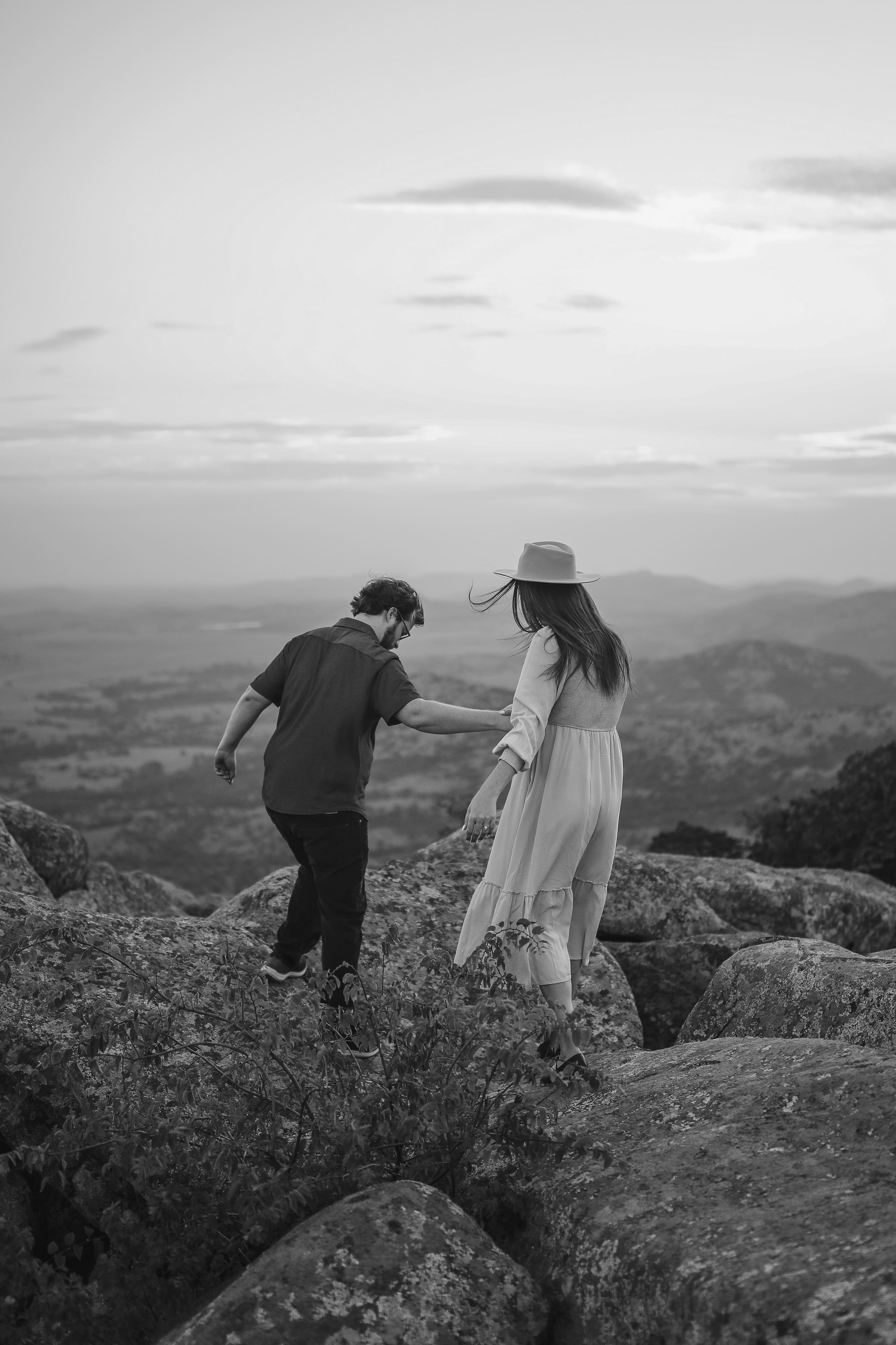 Hand in hand, stepping across the granite as wind lifts her hair