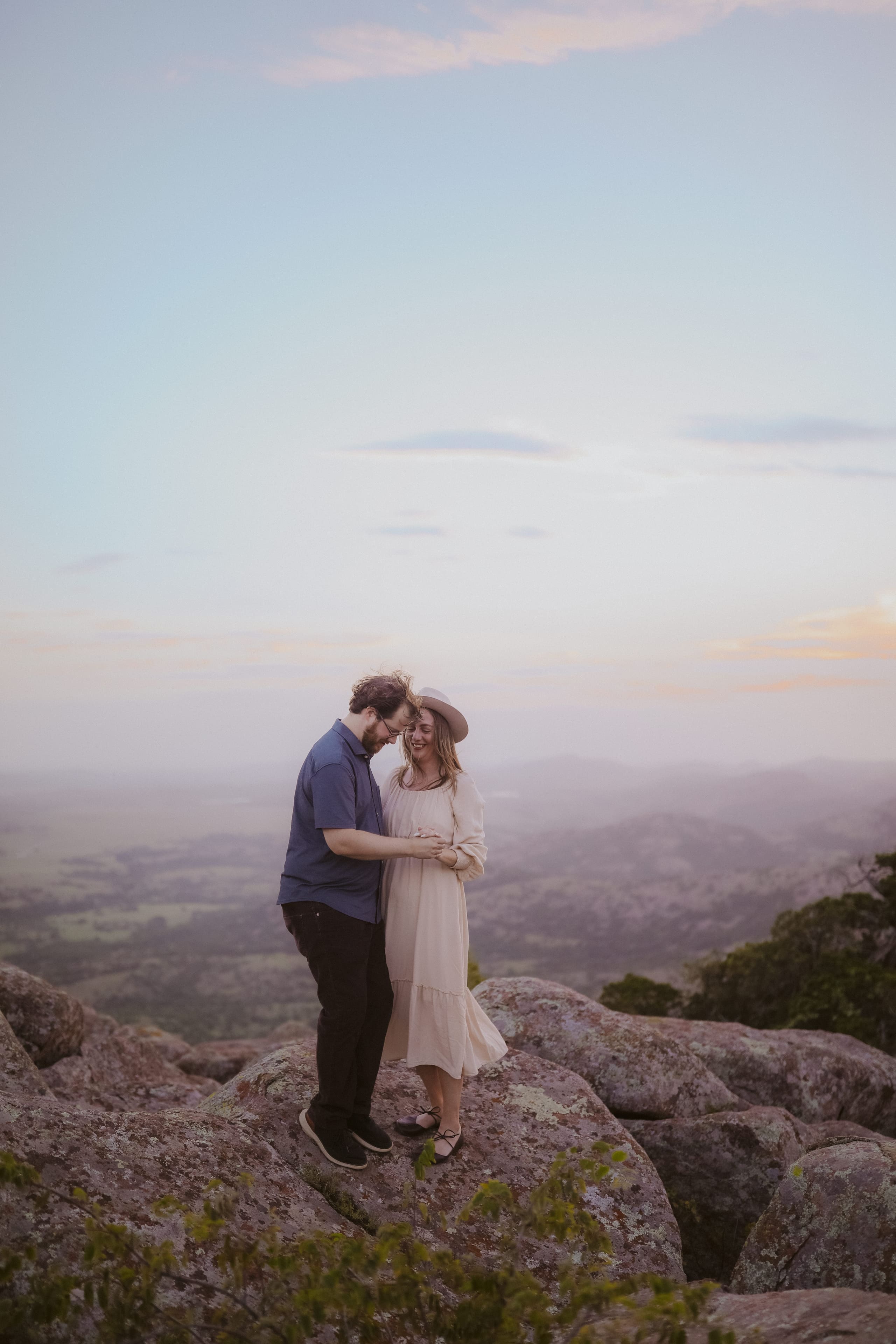 Heads bowed together on the summit, pastel sky all around