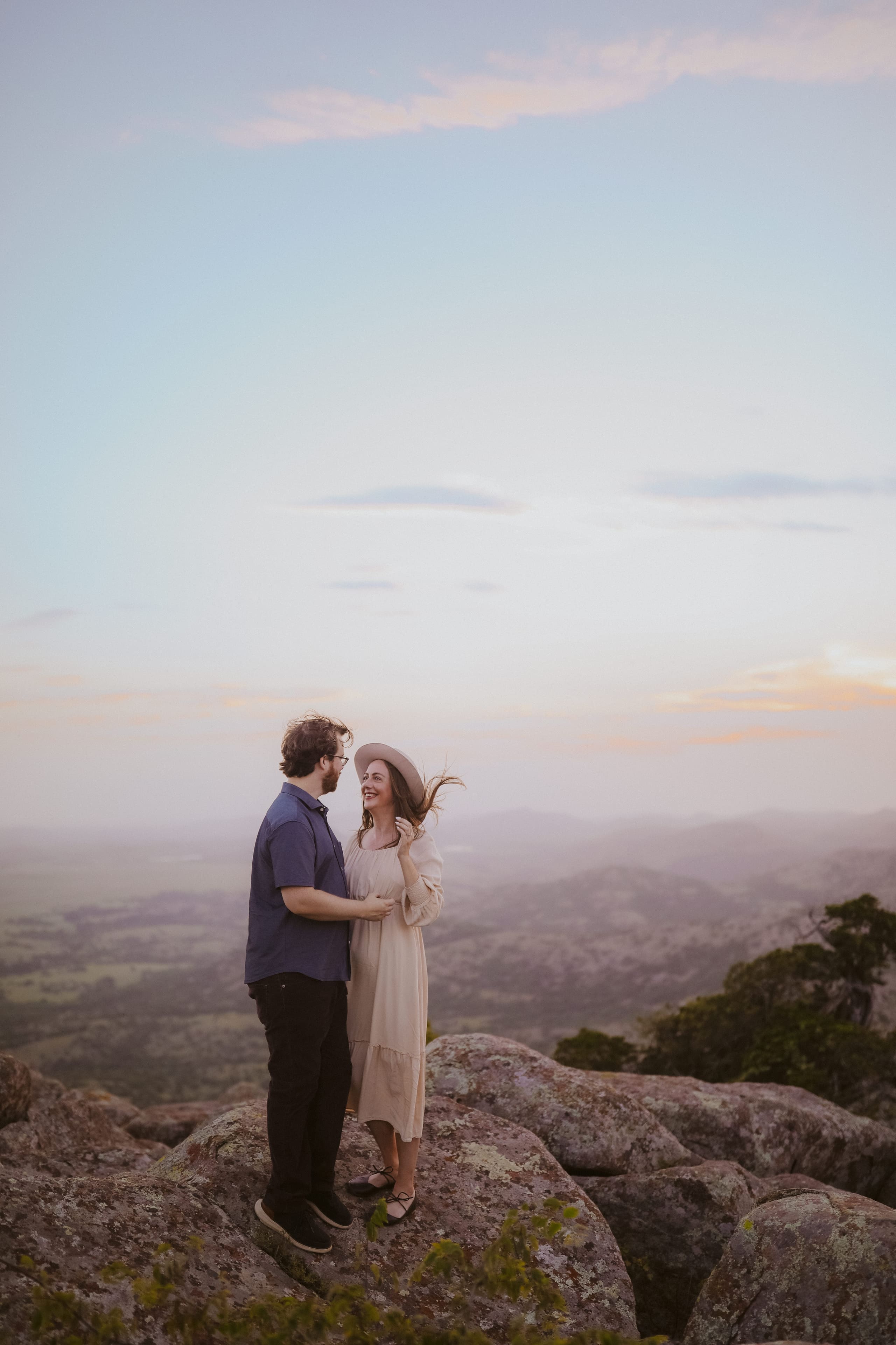 Laughing together on the mountaintop, her hat catching the wind