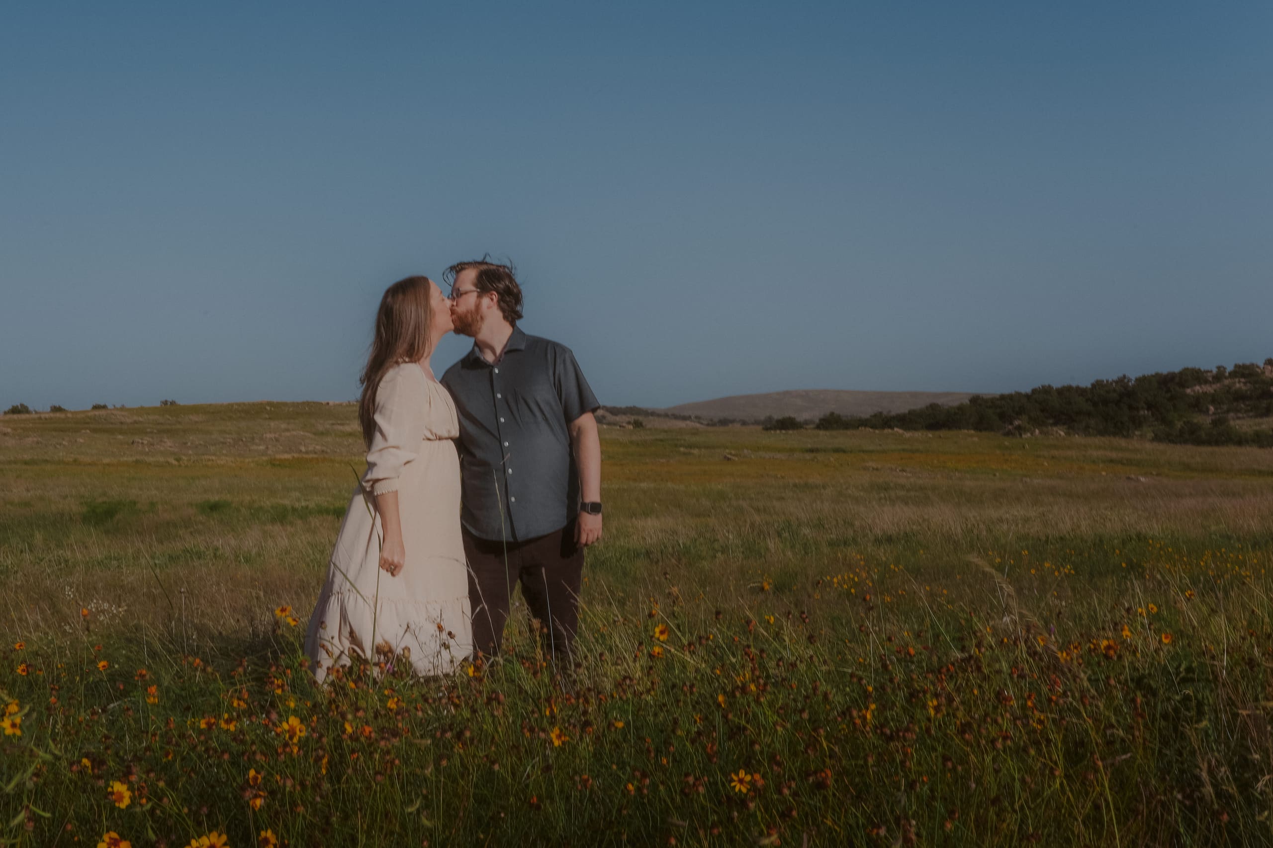 A kiss among the wildflowers, prairie hills on the horizon