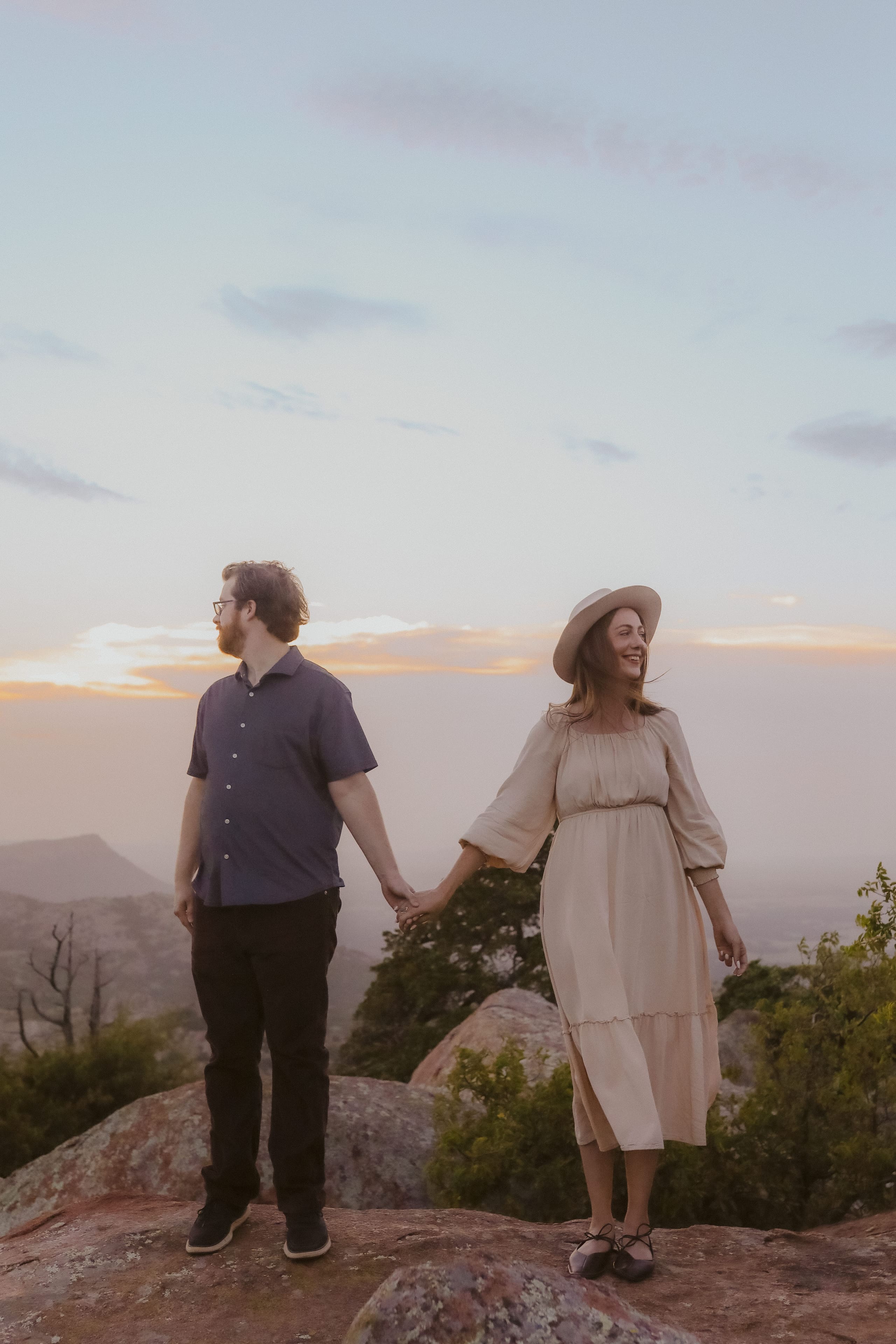 Holding hands at sunset, each gazing toward opposite horizons