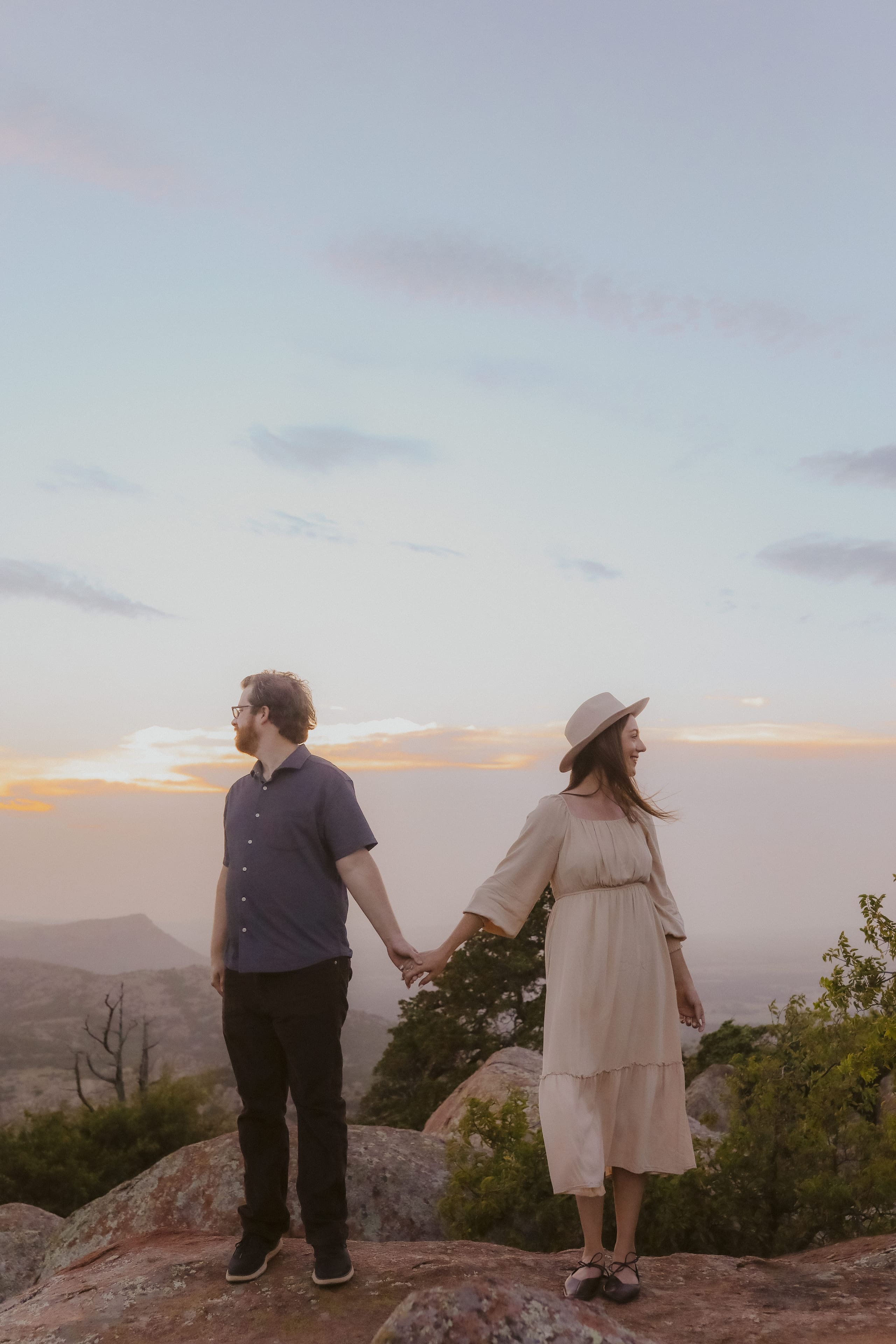 Hand in hand beneath a wide pastel sky on the summit