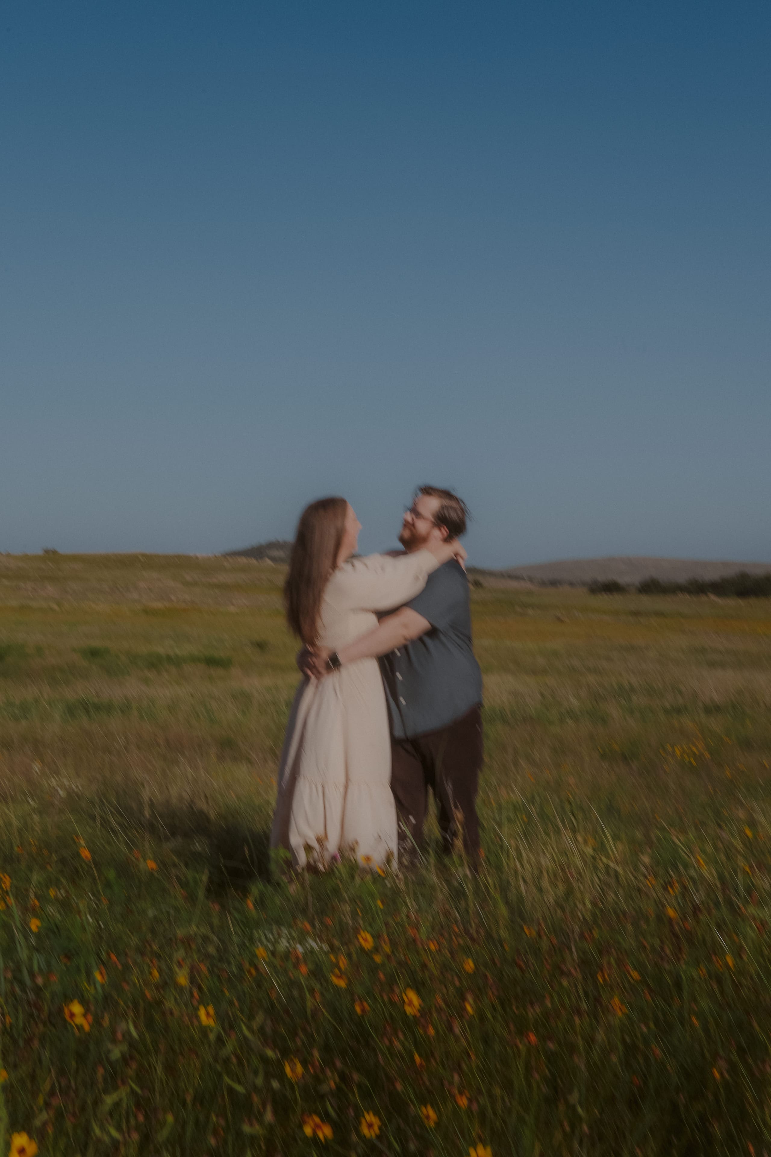 A blurred dance in the wildflower field, arms around each other