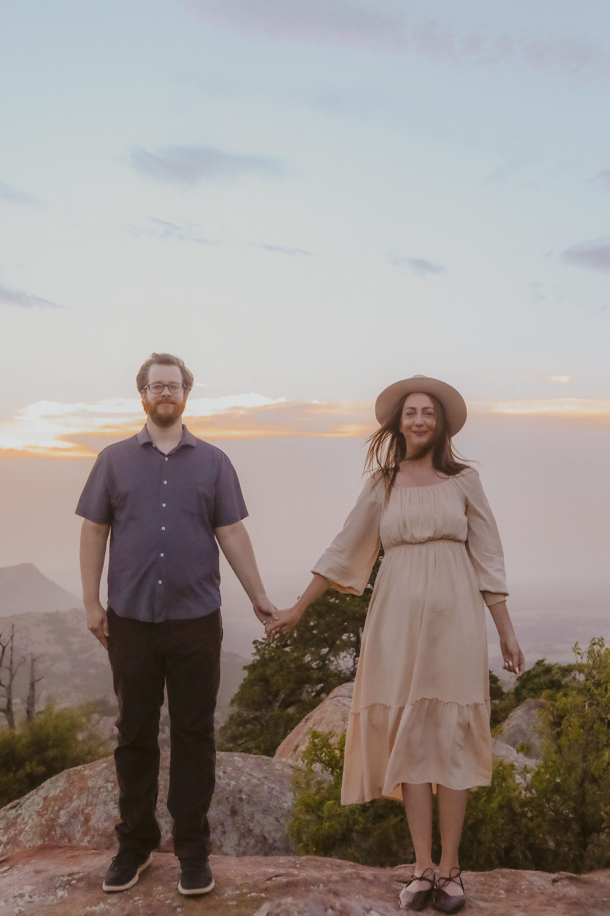 Hand in hand on the mountaintop as the sunset glows behind them