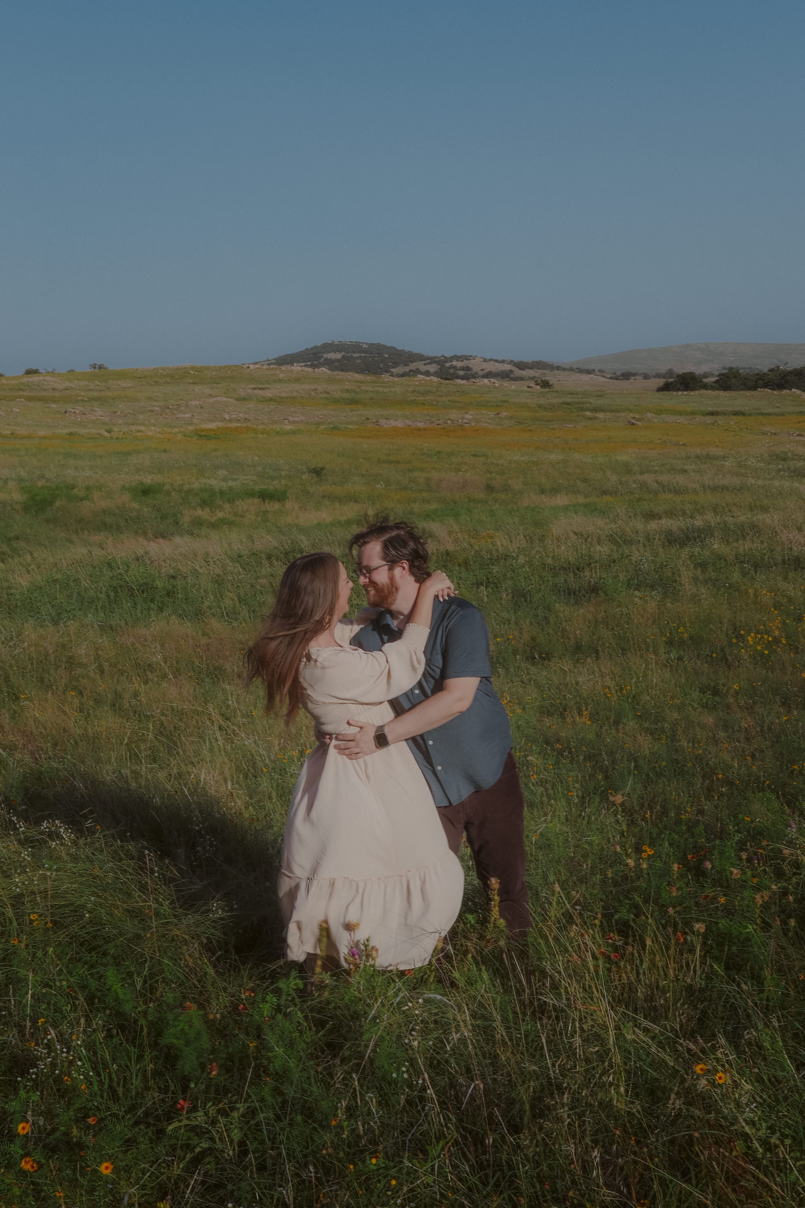Nose to nose in the tall grass, wildflowers scattered at their feet