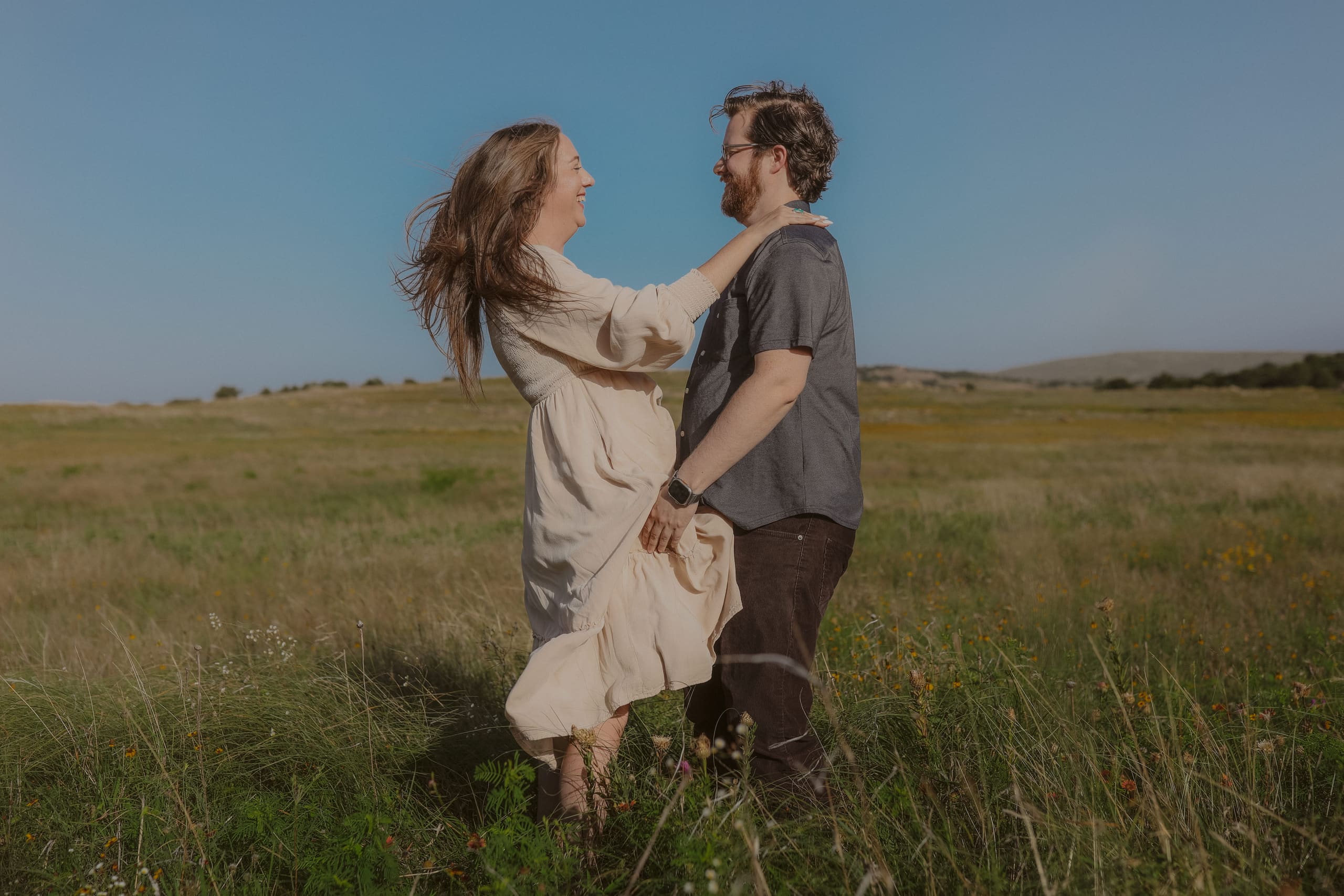 Laughing face to face in the meadow, wind in her hair