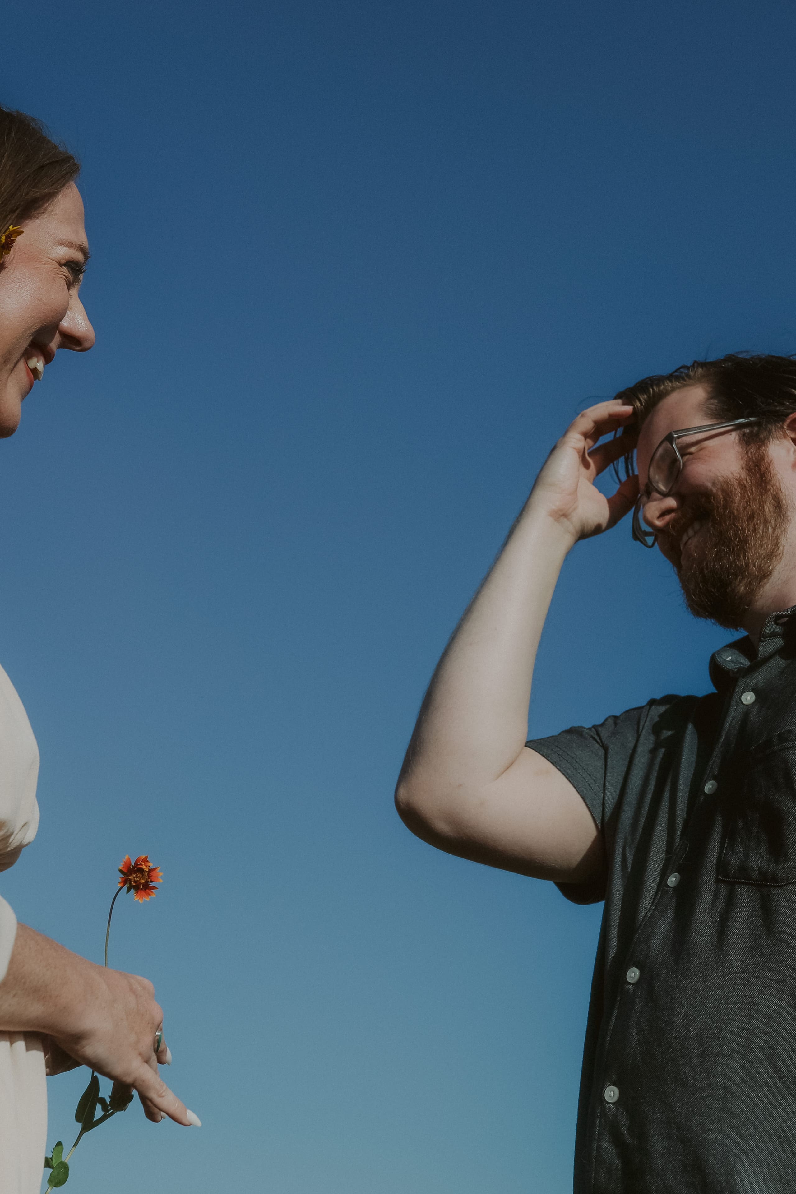 Laughing under the blue sky, a wildflower tucked behind her ear