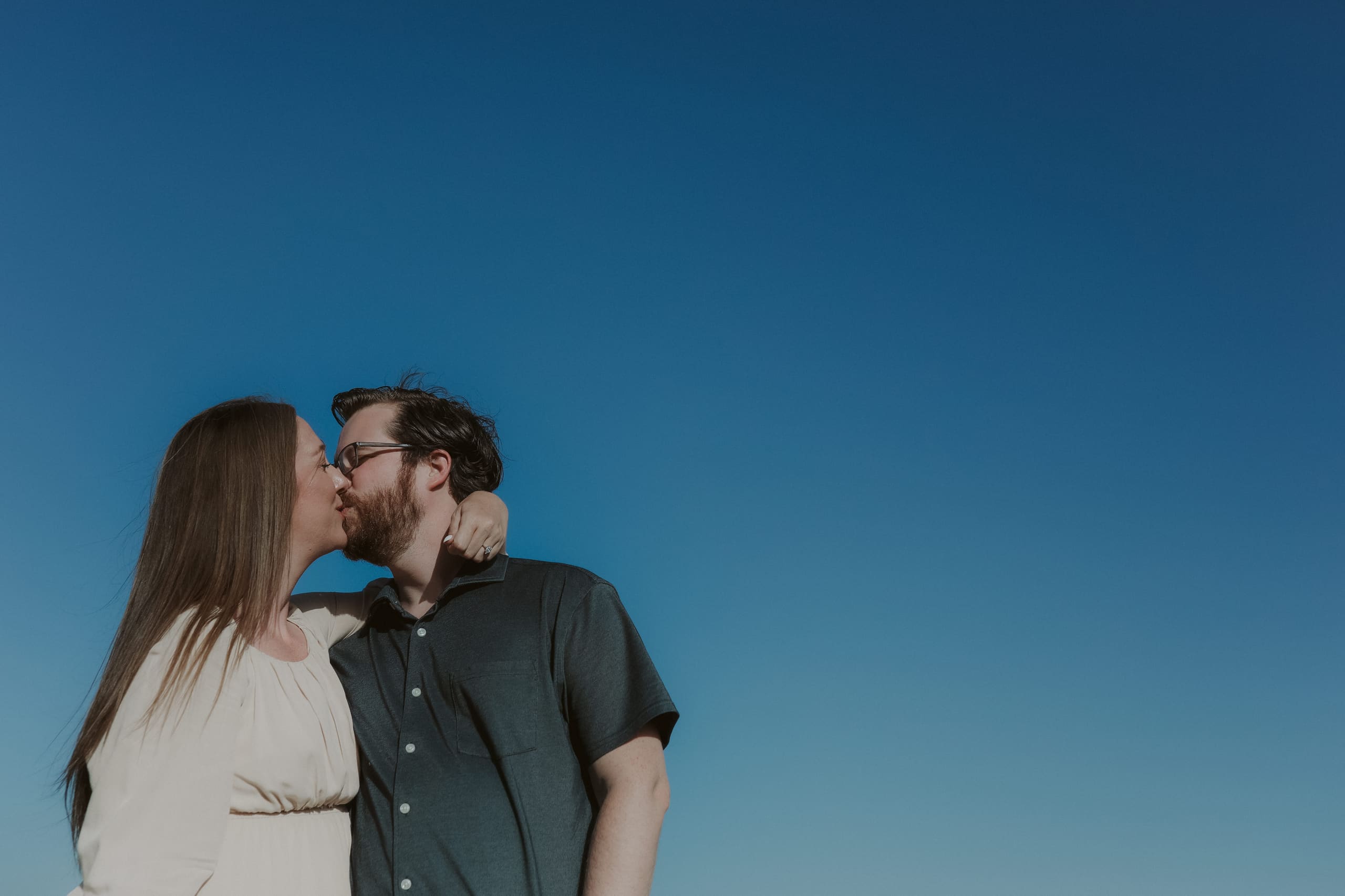 A quiet kiss framed by nothing but open blue sky