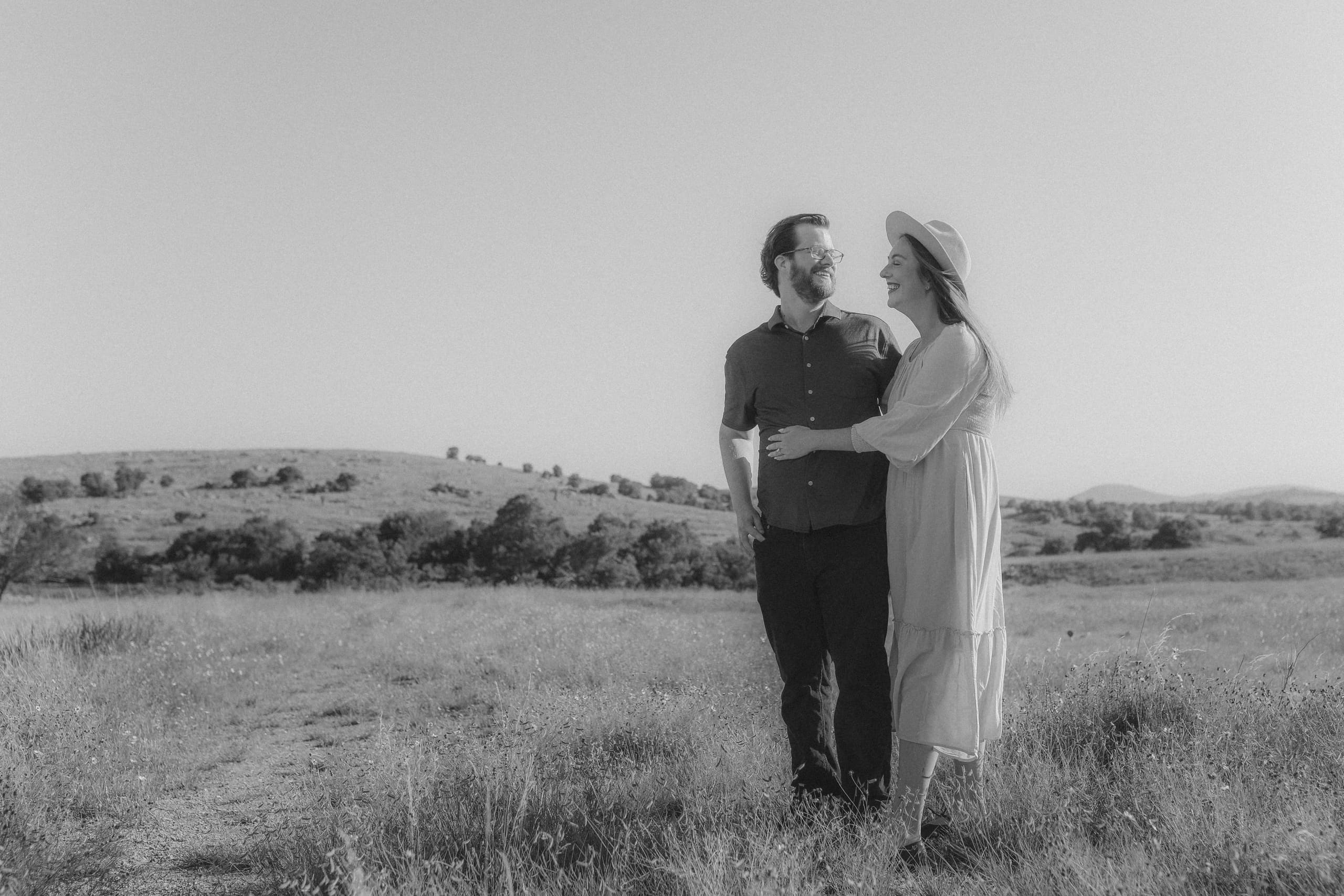 Arm in arm in the tall grass, laughing in black and white