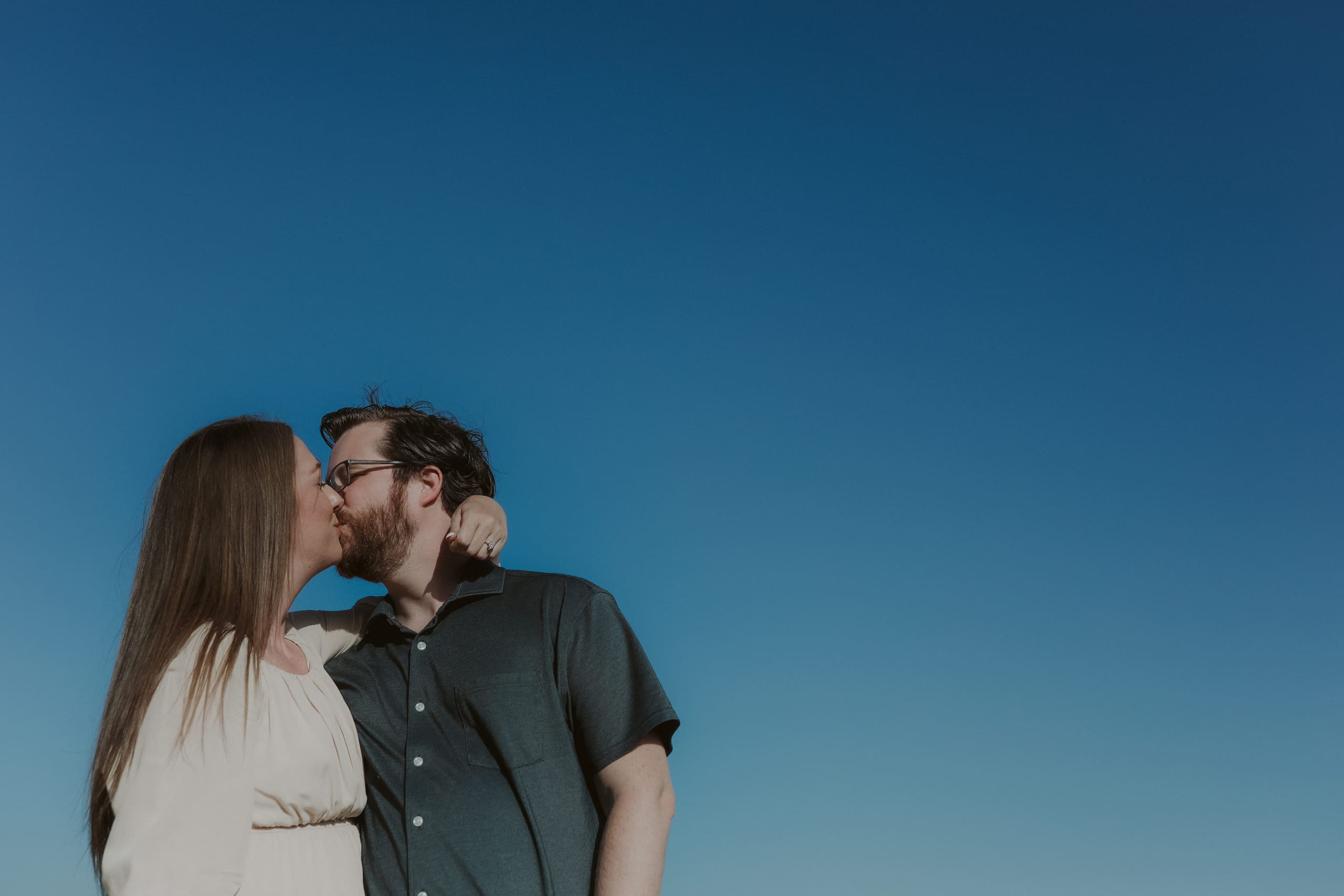 Leaning into a kiss, the sky stretching wide beside them