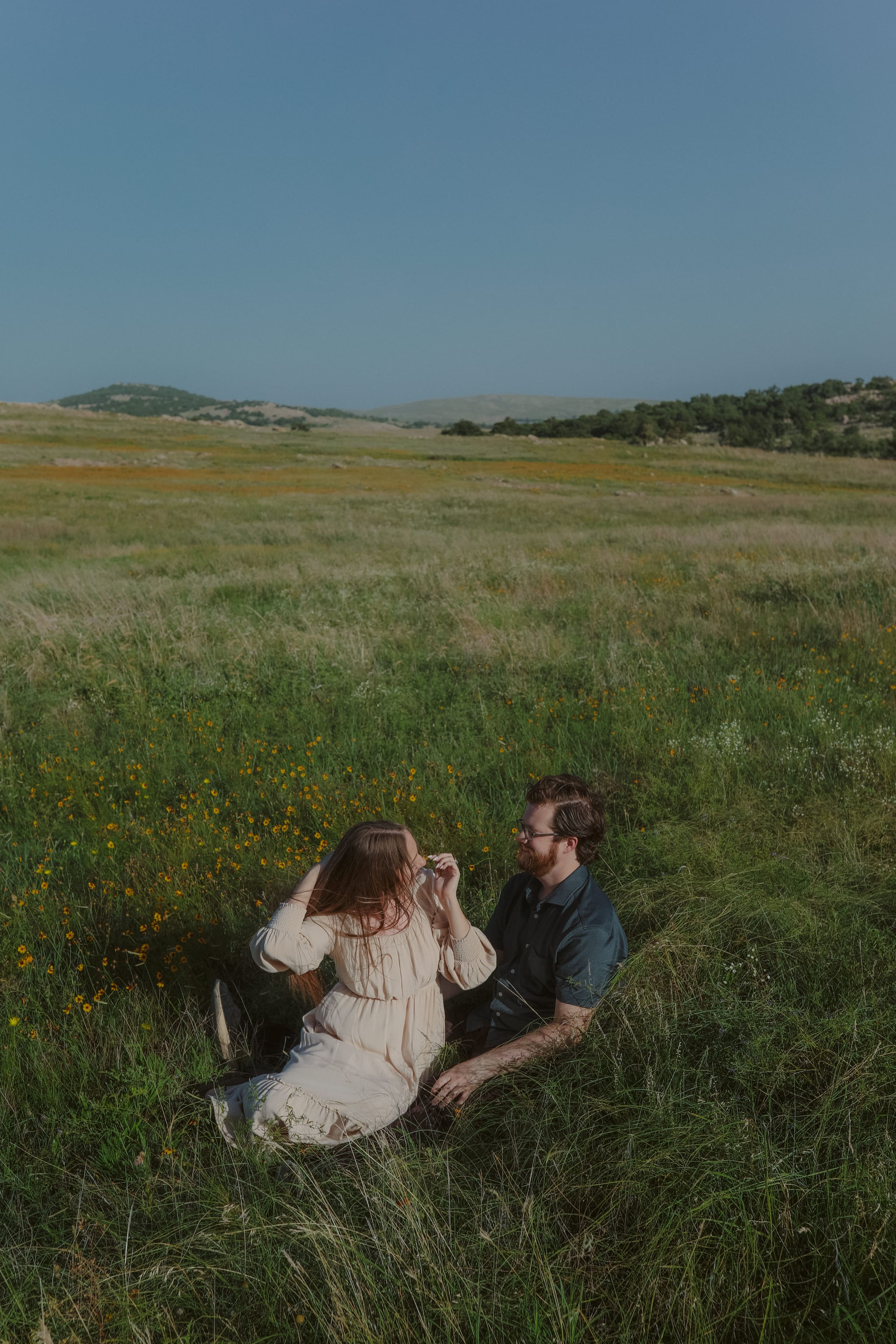 Seated among yellow wildflowers, the prairie rolling out to distant hills