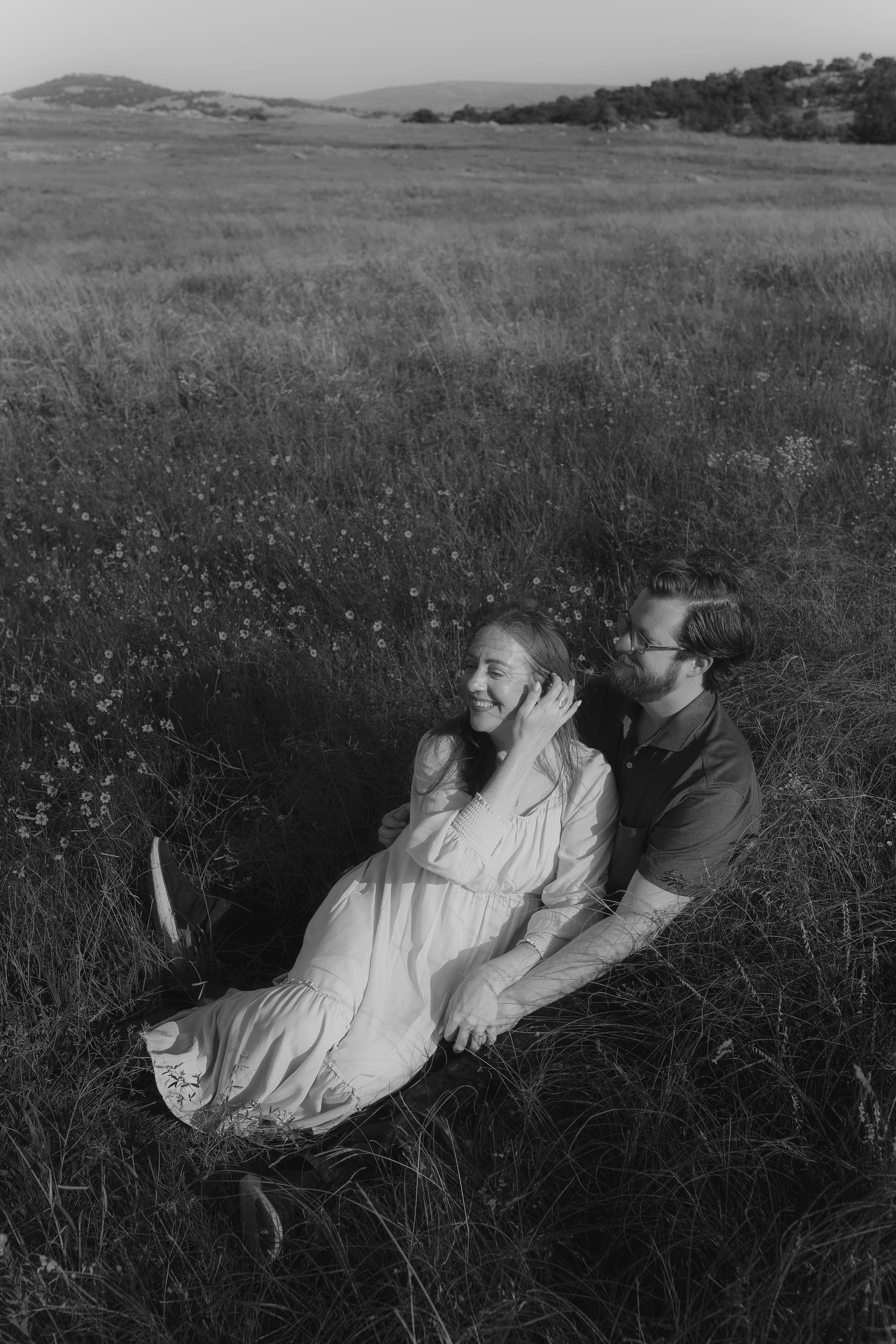A black-and-white moment in the meadow, her laugh caught mid-breeze