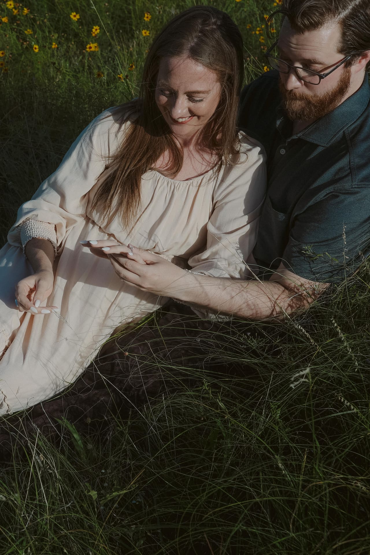 A quiet close moment in the grass, her hand resting in his