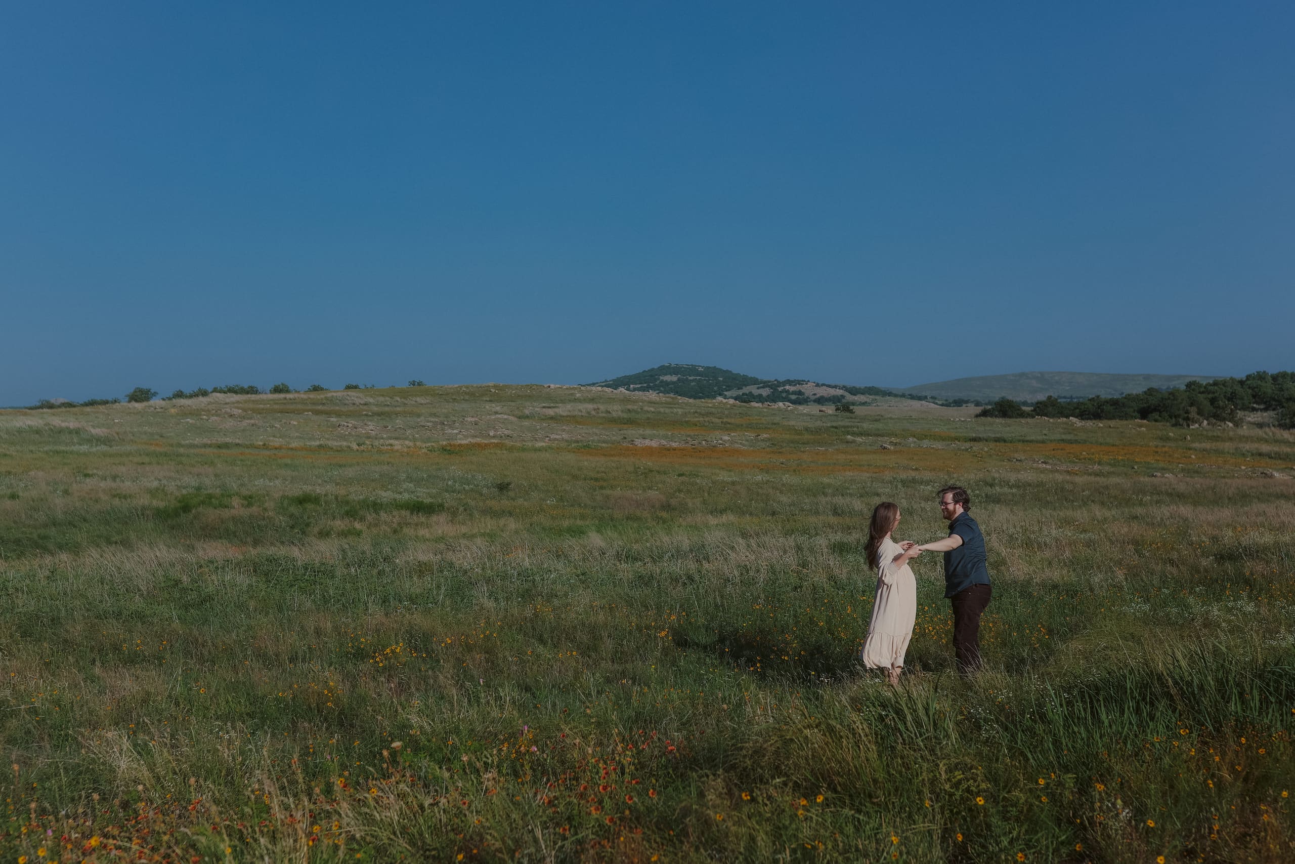Reaching for each other in the open field, wildflowers all around