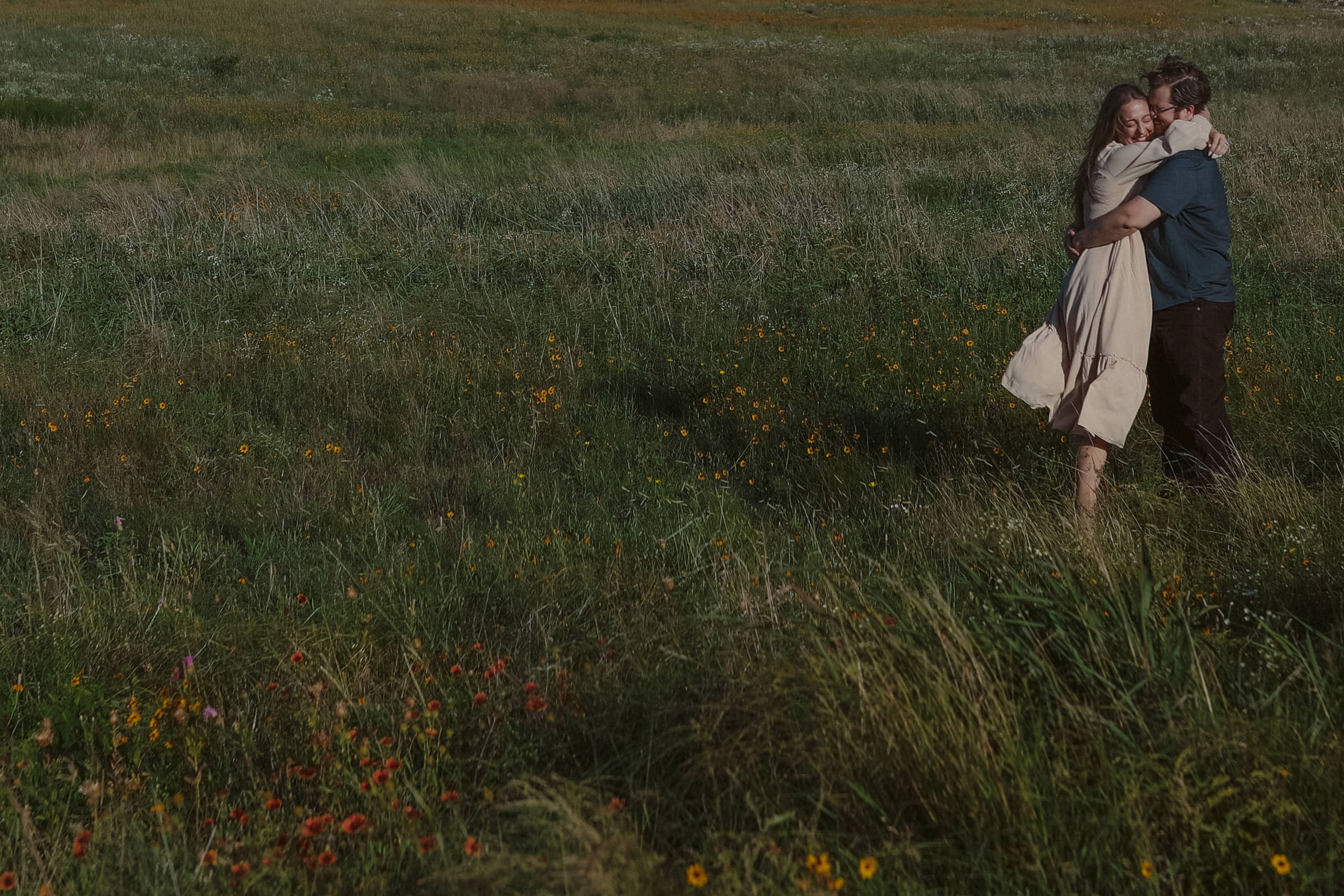 A close embrace in the meadow, her dress catching the breeze