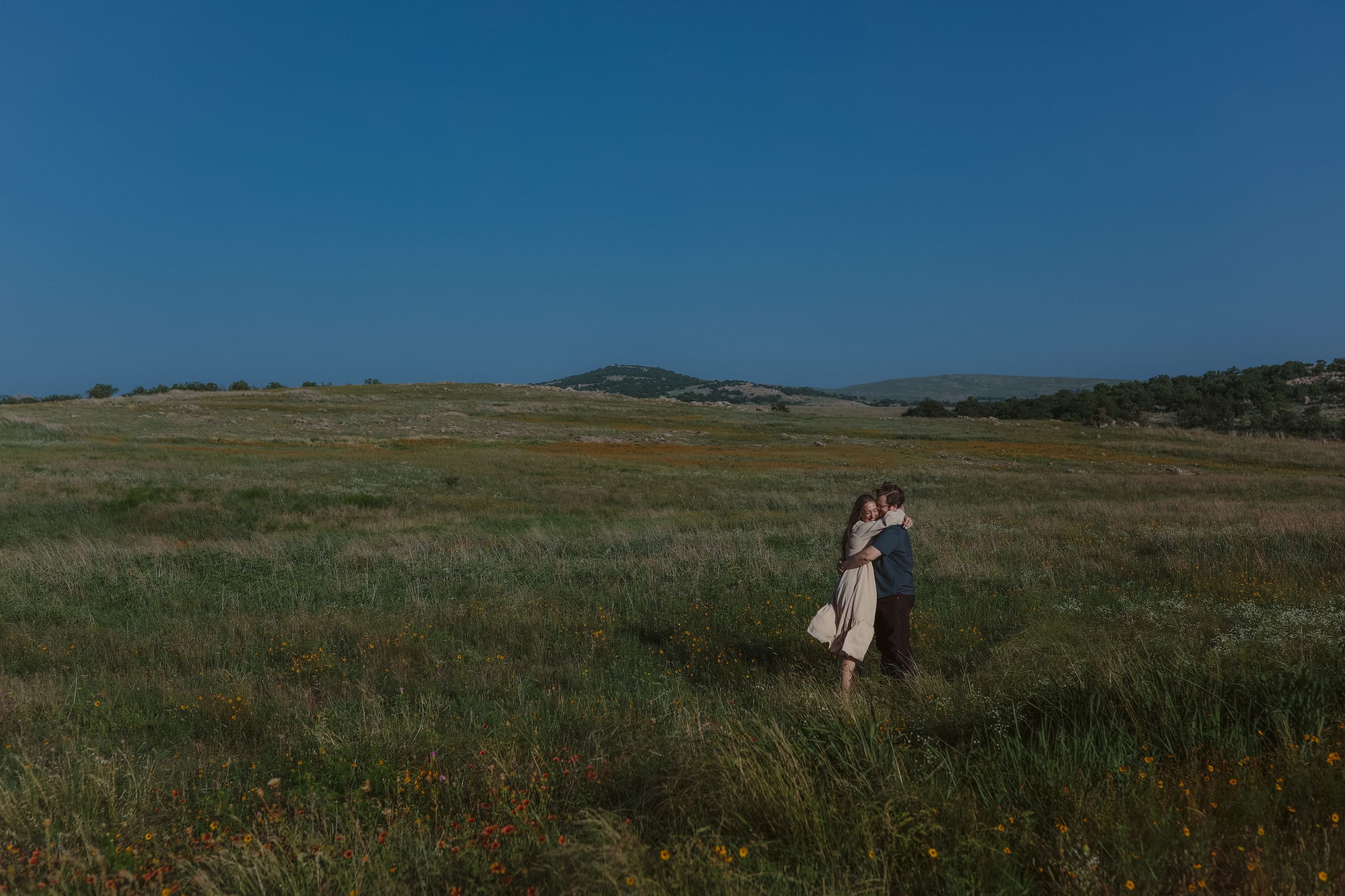 Holding each other in the middle of a wide prairie of wildflowers