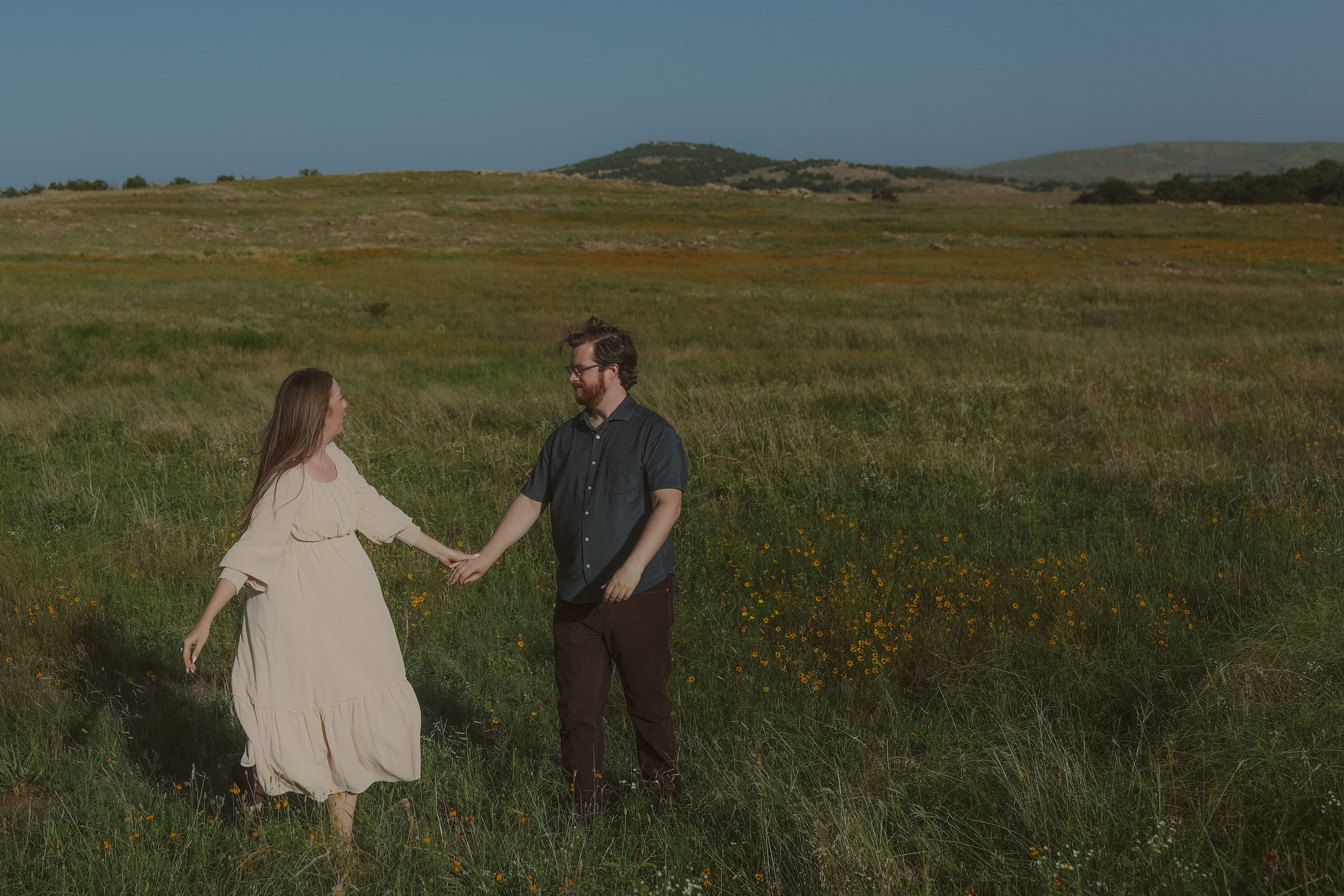 Hand in hand crossing the meadow, hills rising in the distance