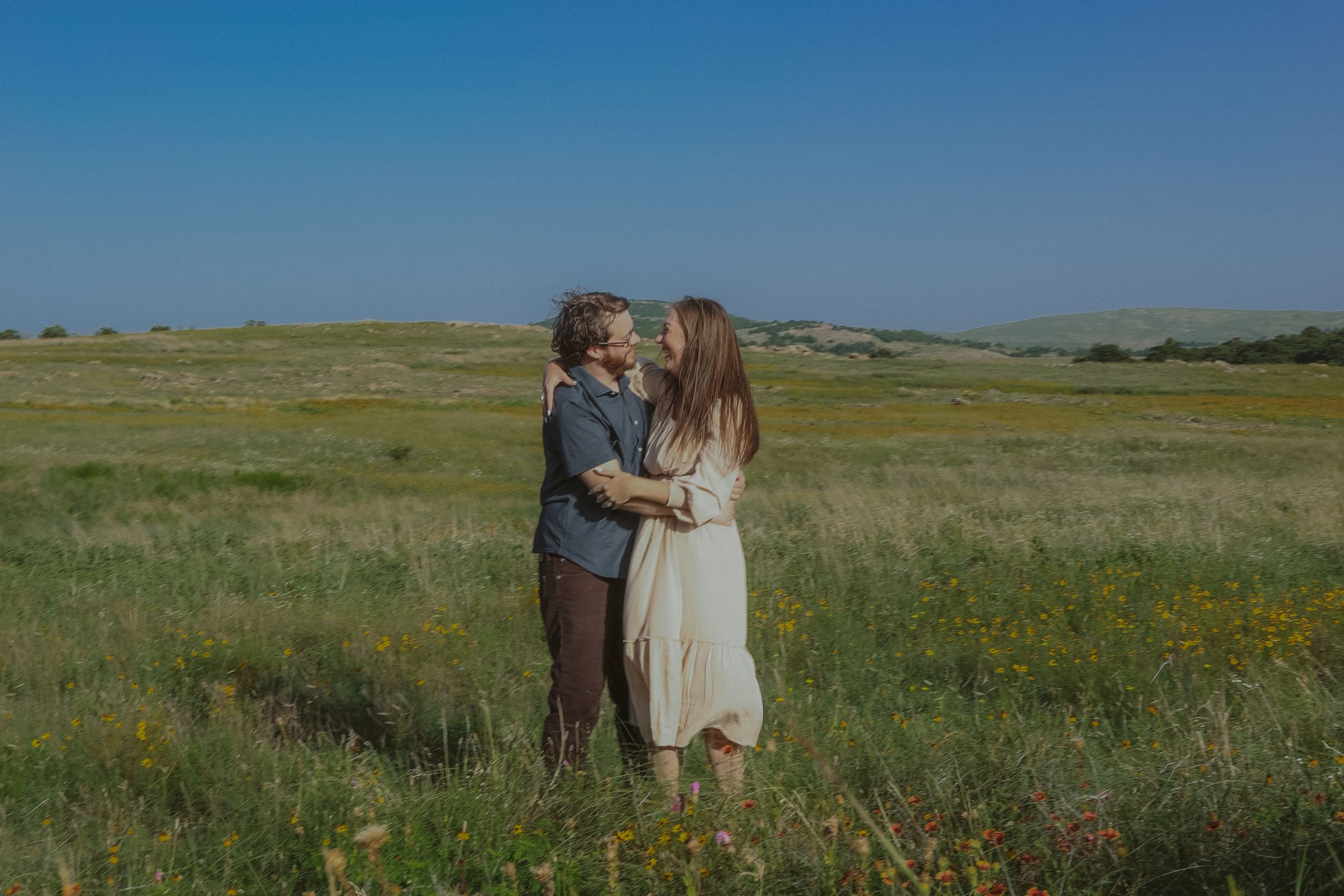 Wrapped in an embrace among the wildflowers, hills in the distance