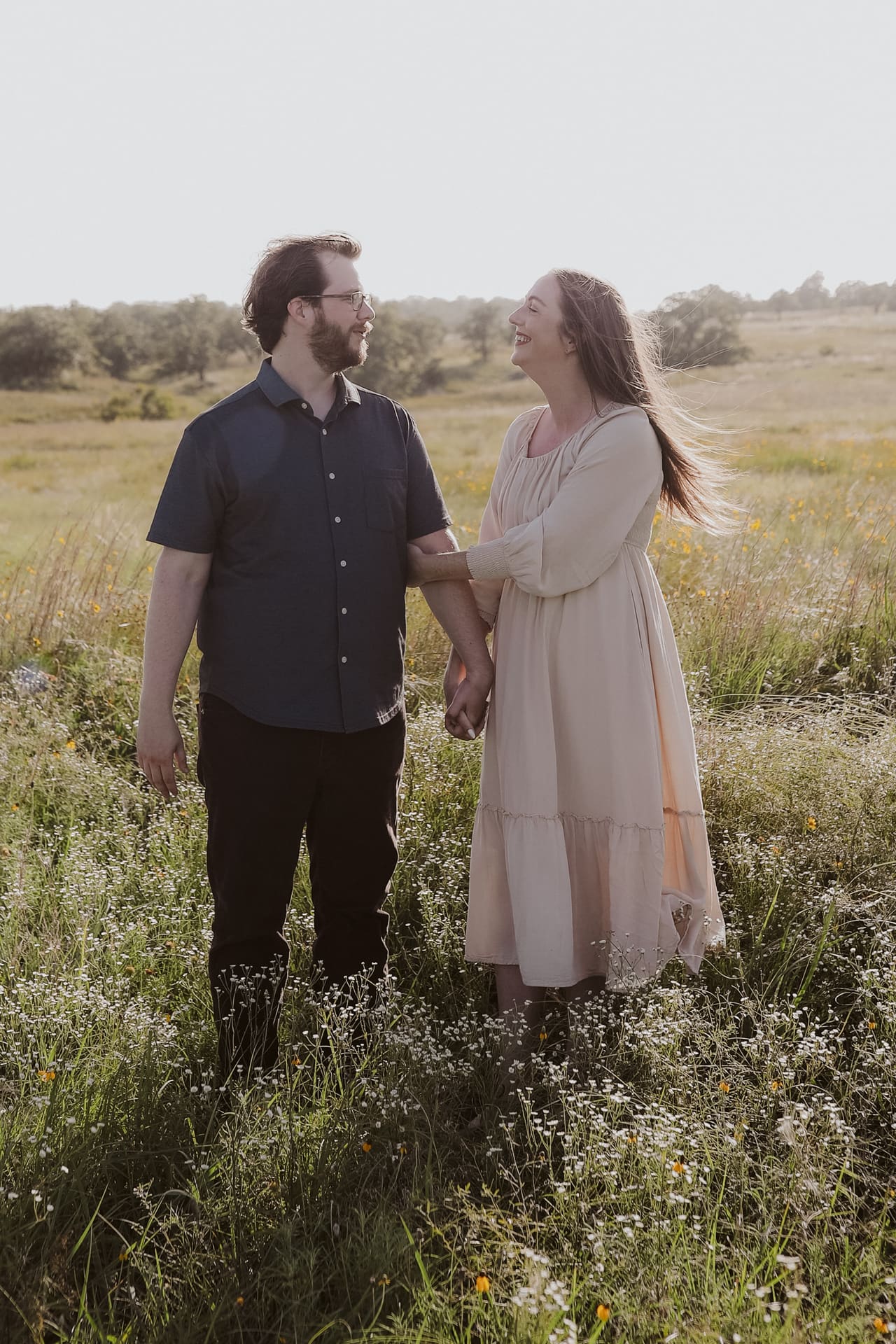 Face to face in the wildflowers, laughing hand in hand in the sun