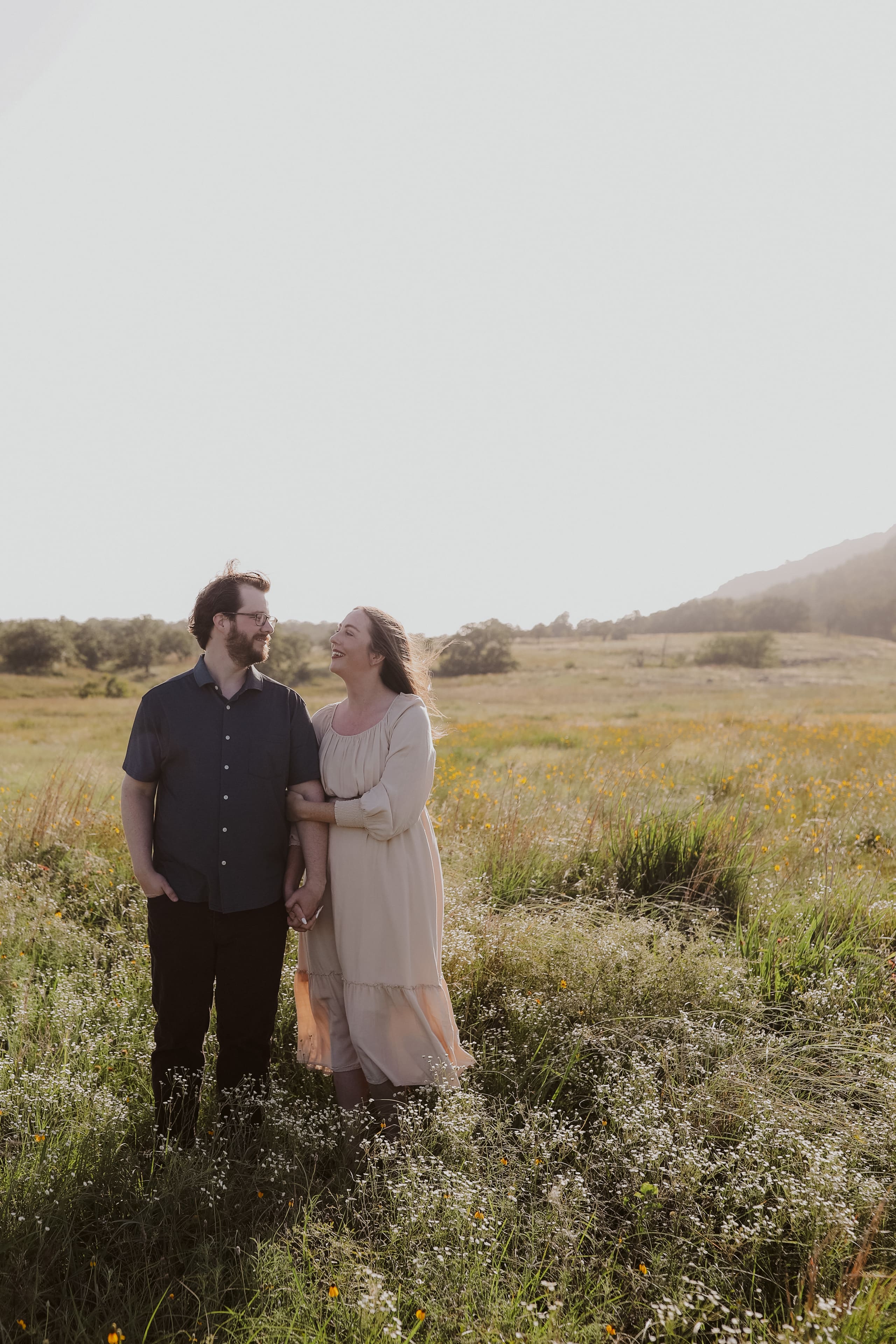 Laughing together in a sunlit meadow, arm in arm at golden hour