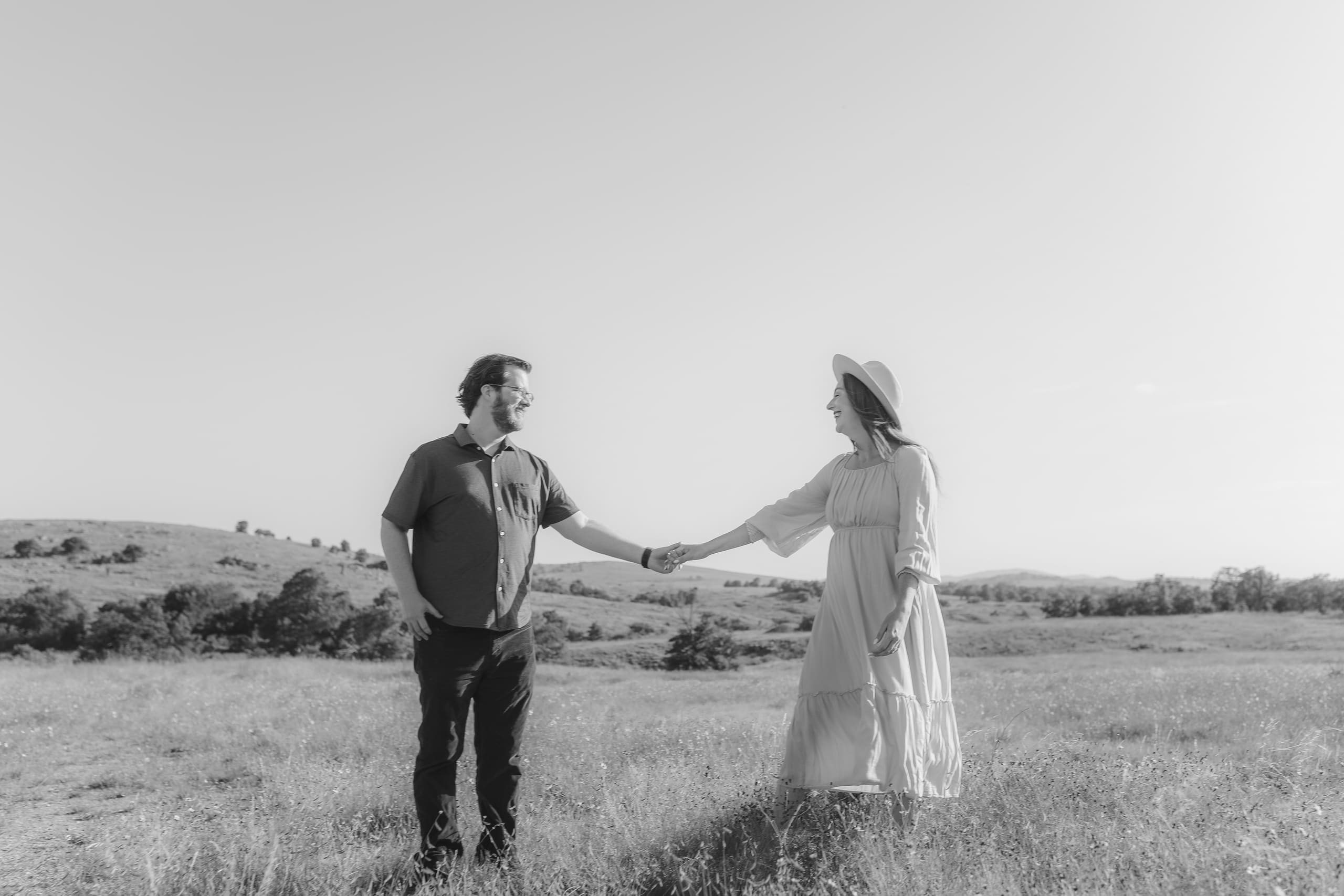 Hands clasped at arm’s length beneath a wide prairie sky, in black and white