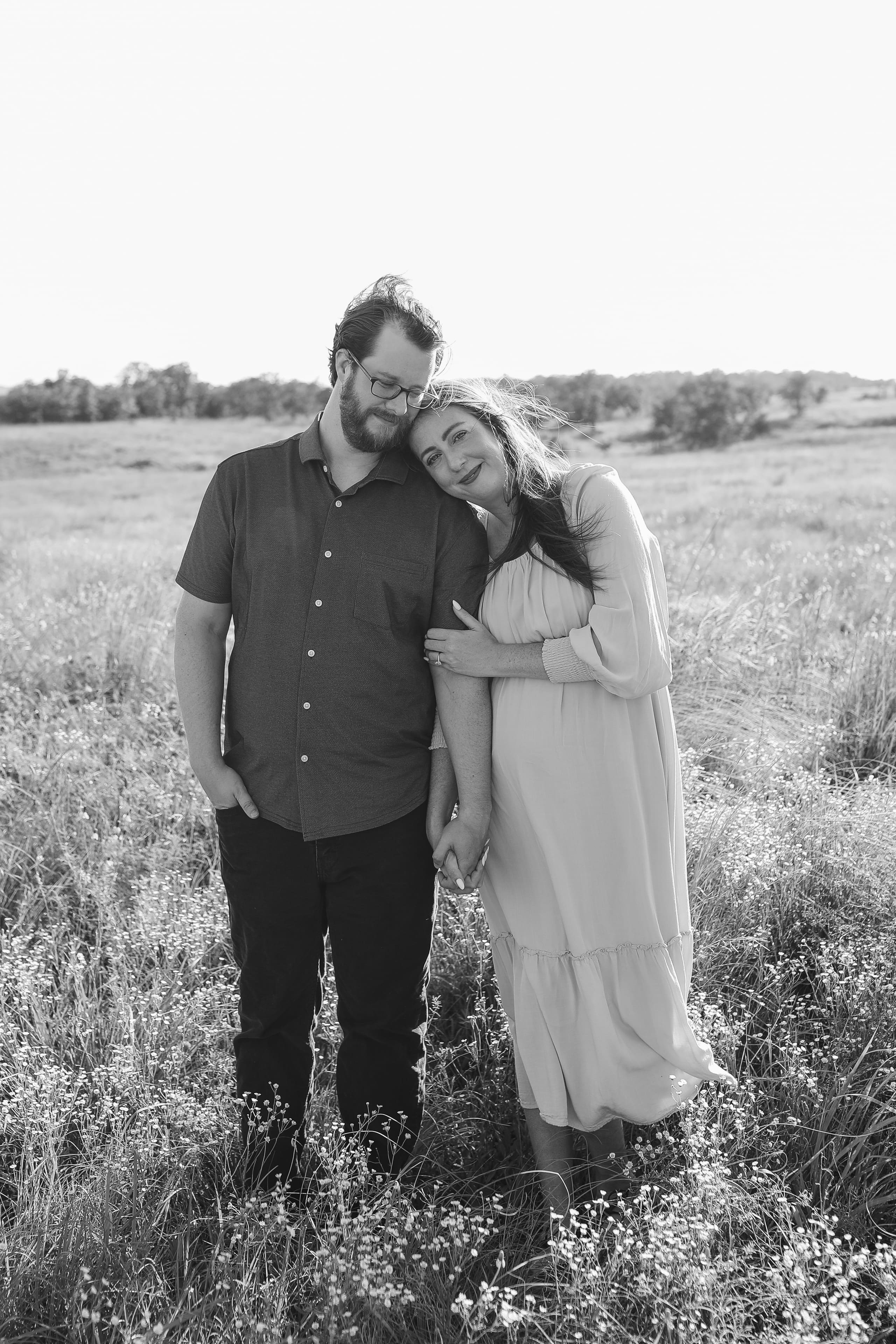 A gentle lean and clasped hands in the flowering grass, in black and white