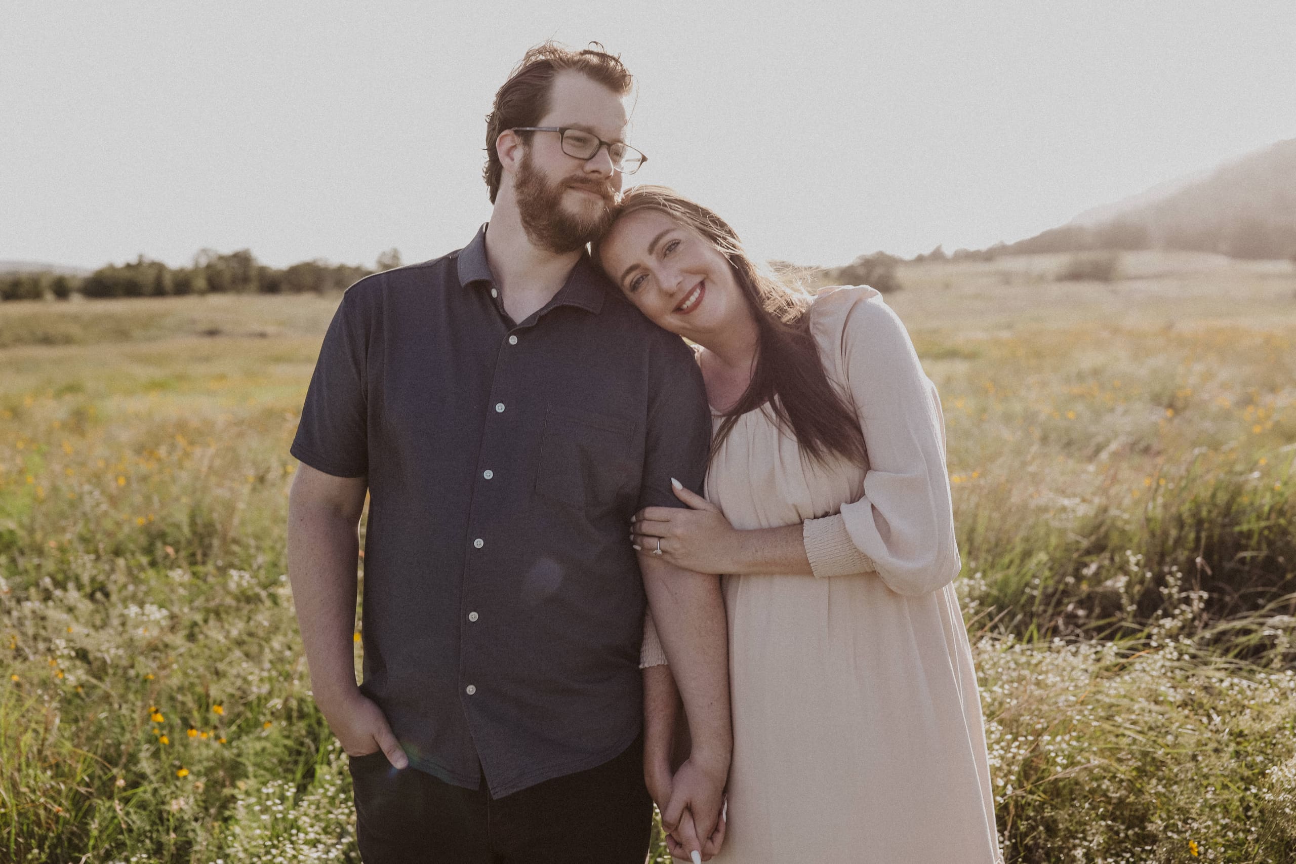 Cheek to shoulder, smiling in the backlit field at golden hour